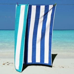 Blue and white striped luxury velour beach towel folded on a sun lounger