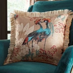 dunelm Mariba Gold Peacock Cushion Cover on teal velvet armchair – bold exotic bird and floral print with fringed edge