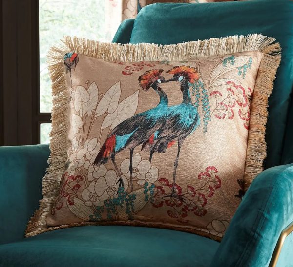 dunelm Mariba Gold Peacock Cushion Cover on teal velvet armchair – bold exotic bird and floral print with fringed edge