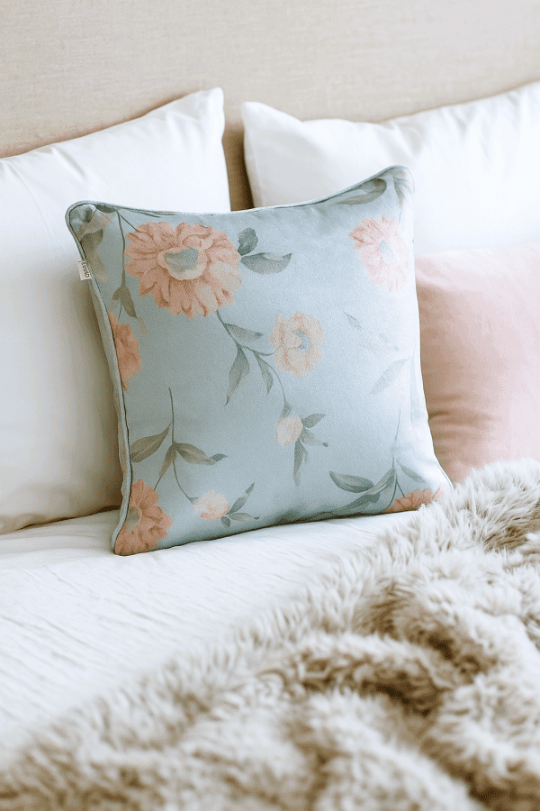 dahlia duck egg cushion on bed floral botanical design in duck egg blue with soft pink flowers