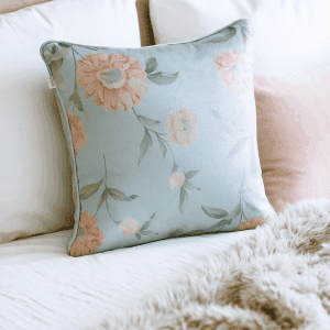 dahlia duck egg cushion on bed floral botanical design in duck egg blue with soft pink flowers