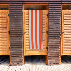 orange white striped bath towel hanging over wooden door