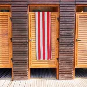 red striped towel. red and white striped bath towel hanging over wooden door