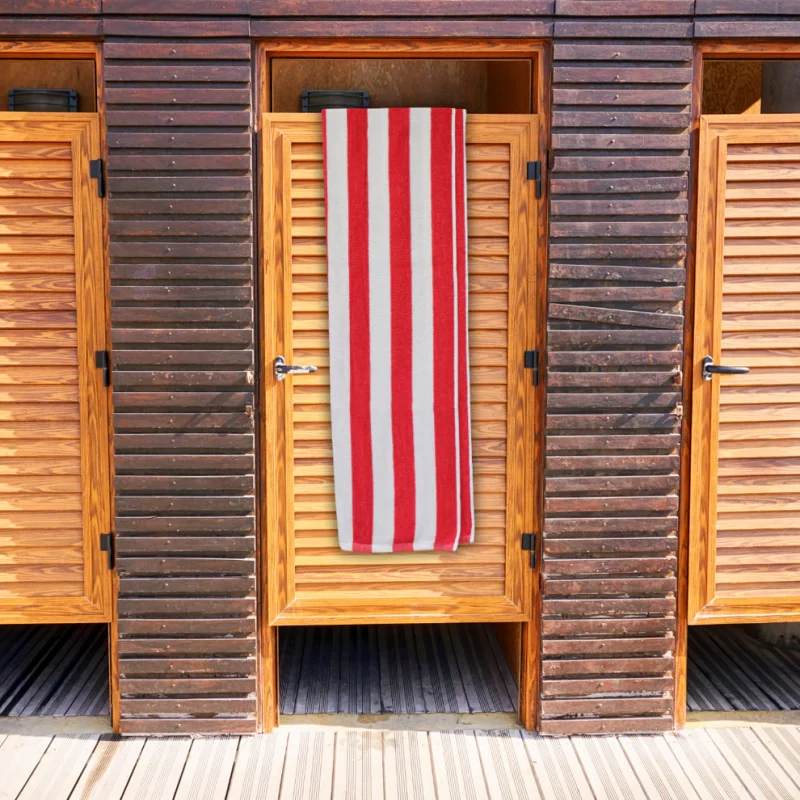 red striped towel. red and white striped bath towel hanging over wooden door